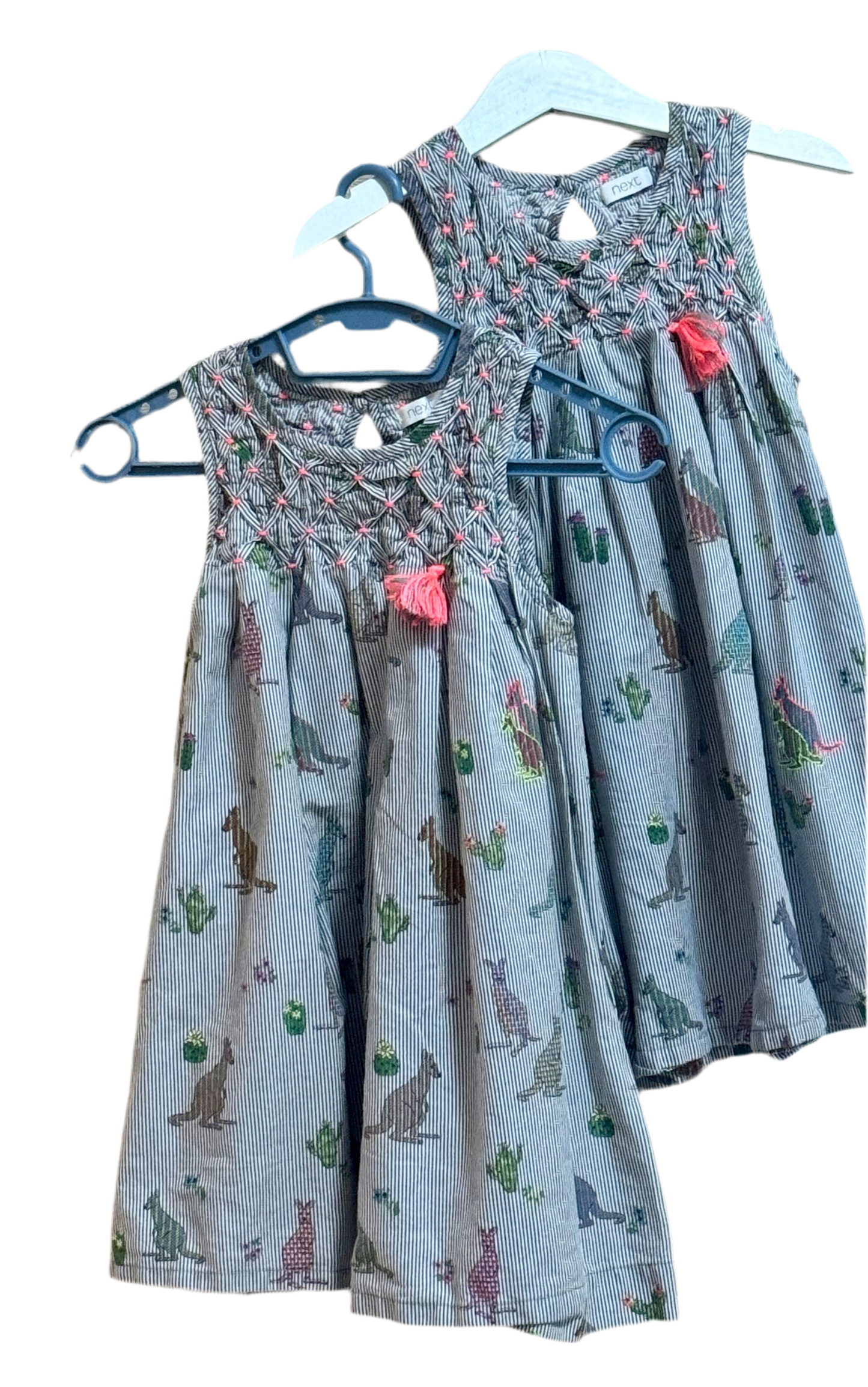 Two dresses with floral and animal print designs on a gray background, displayed on hangers.